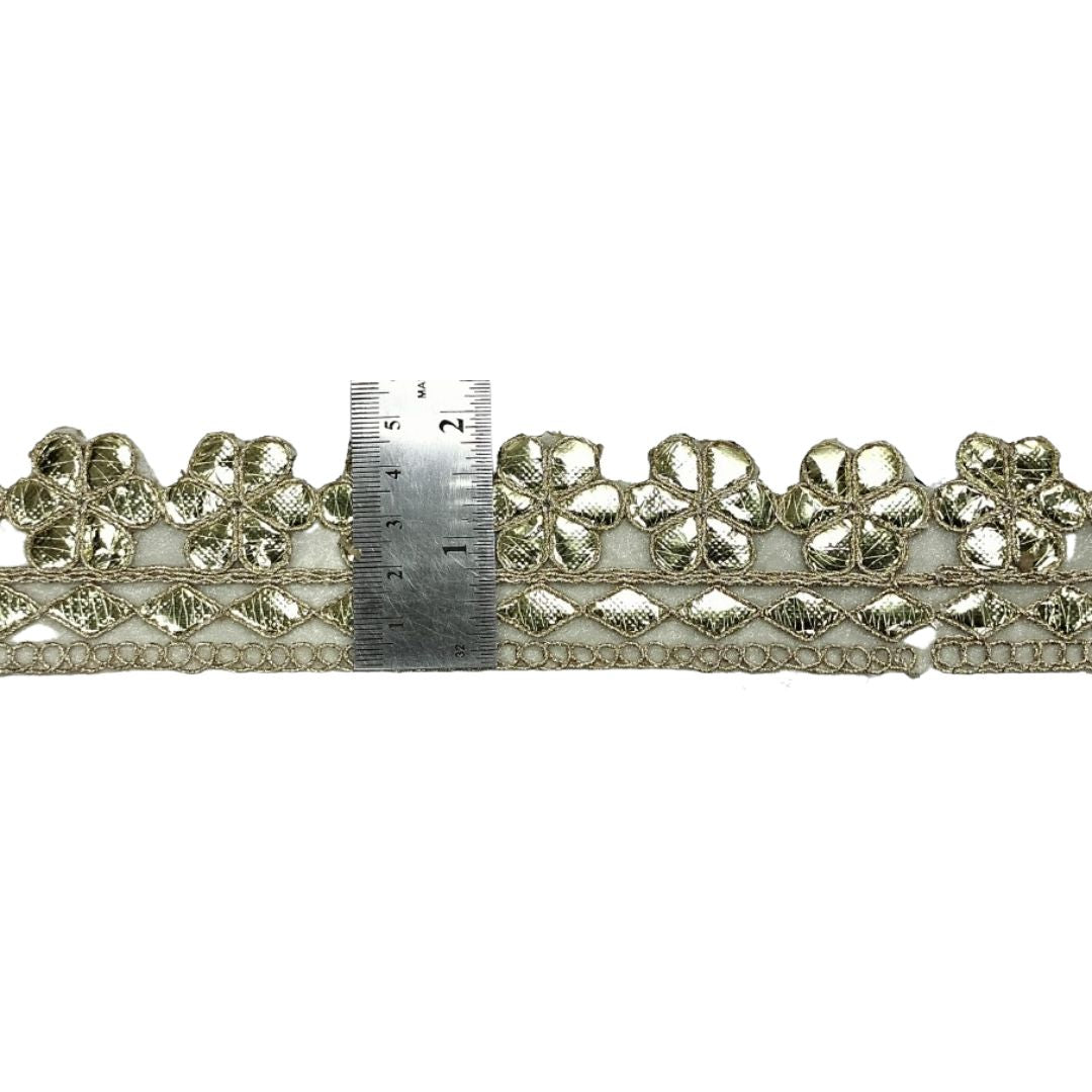 Decorative lace trim with a ruler for scale on a white background